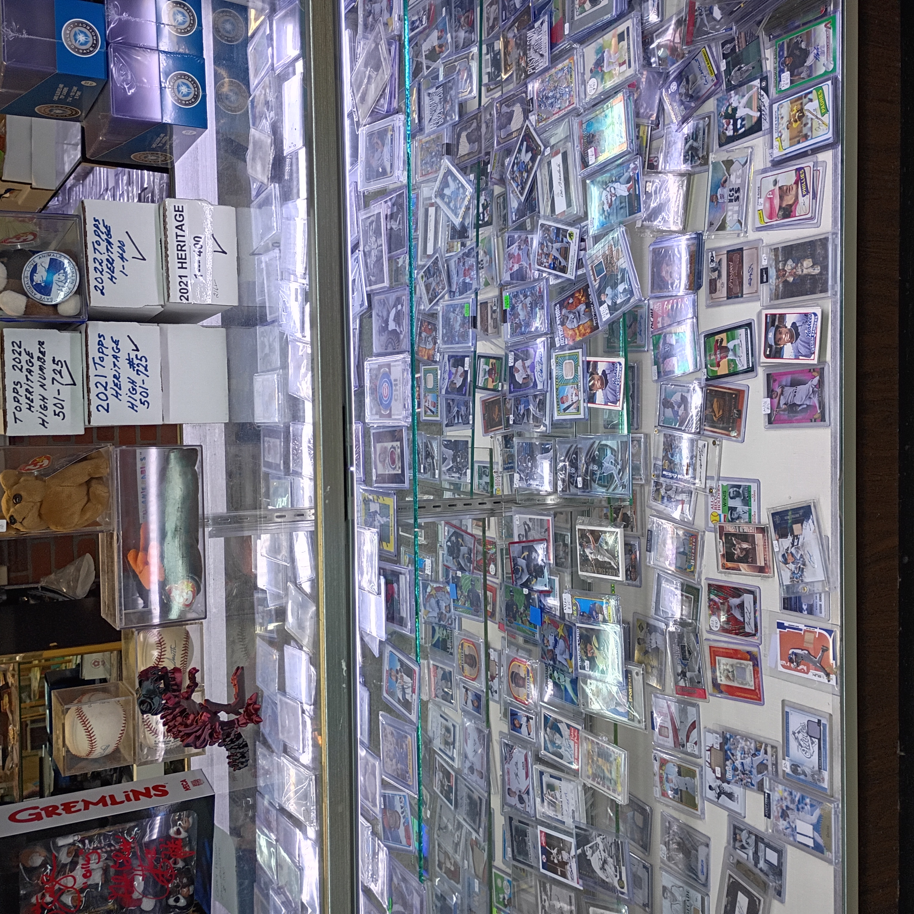 Wall of sports cards in toploaders and penny sleeves in a lit display case at Finn McCool's.